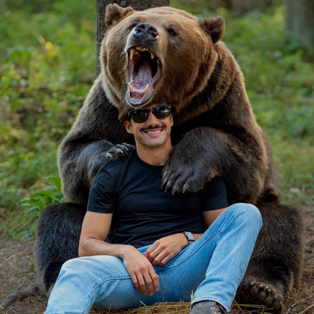 O João sentado à frente de um urso pardo